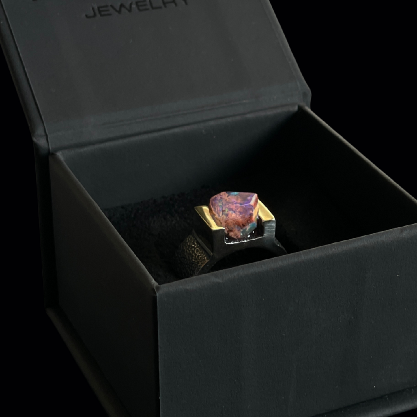 Ring with a colorful Mexican opal gemstone in a black jewelry box